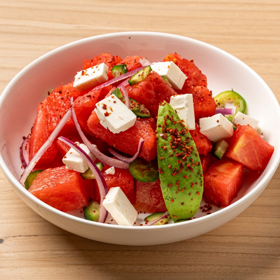 Nour's Lebanese watermelon salad with feta, red onion, avocado, and chili flakes in a white bowl.