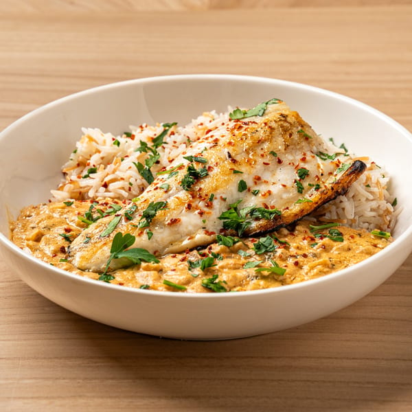 Nour's Lebanese dish with grilled fish, rice, and a creamy sauce, garnished with parsley.